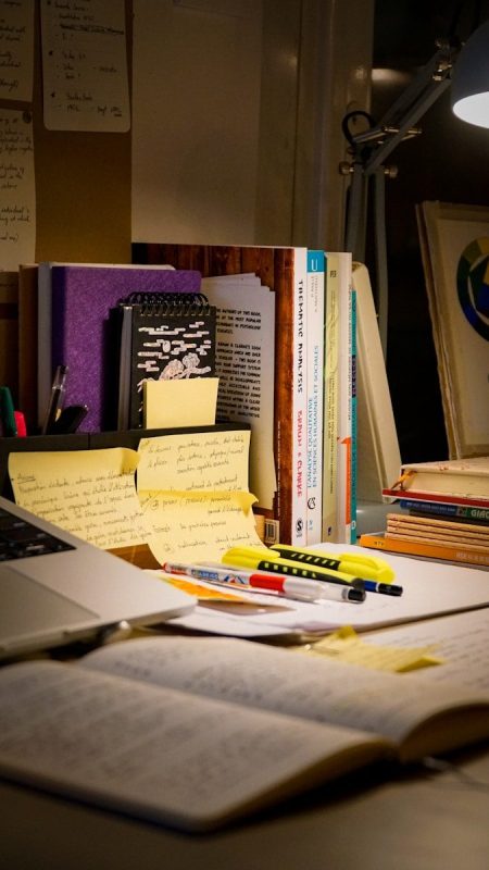 Desk with open book, laptop, and study materials.