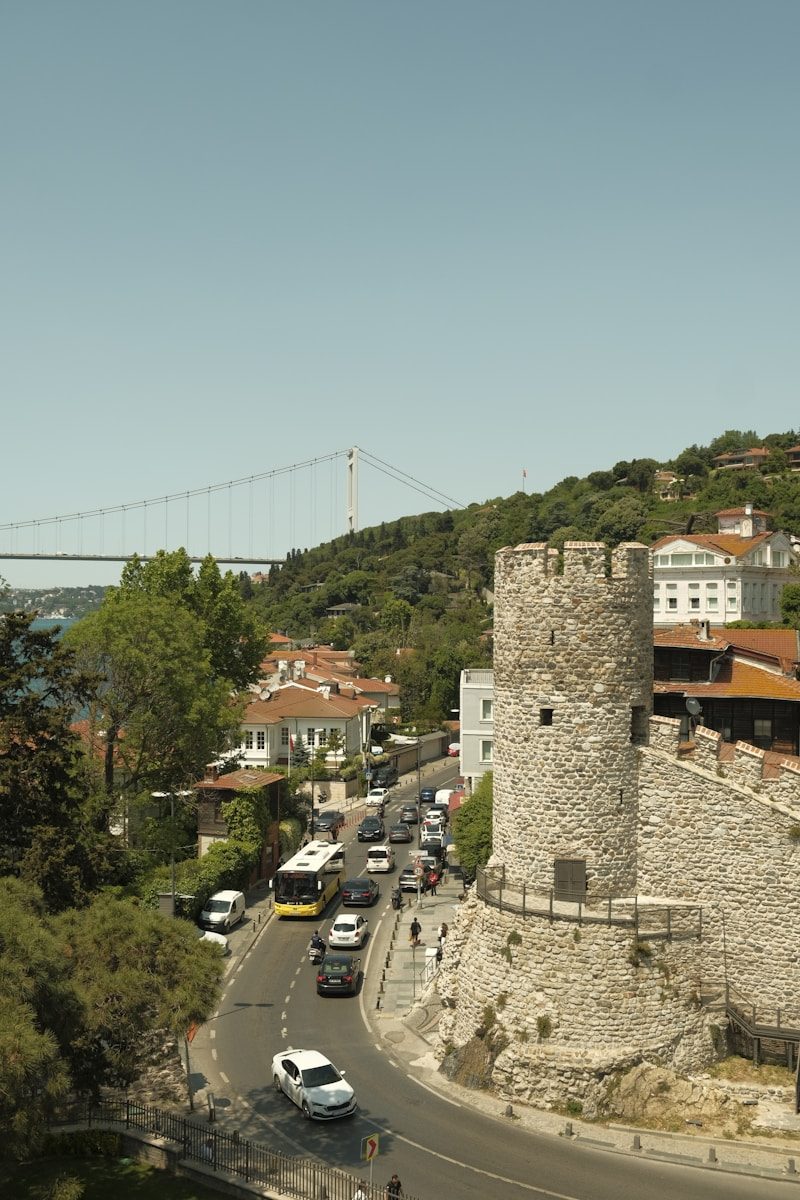 Stone tower and wall overlooking a busy street and bridge.