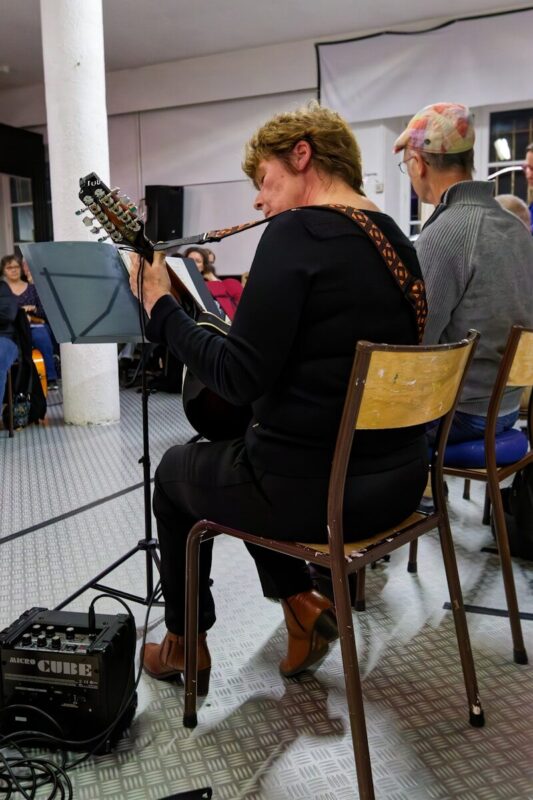 A musician plays a stringed instrument with an amplifier nearby.